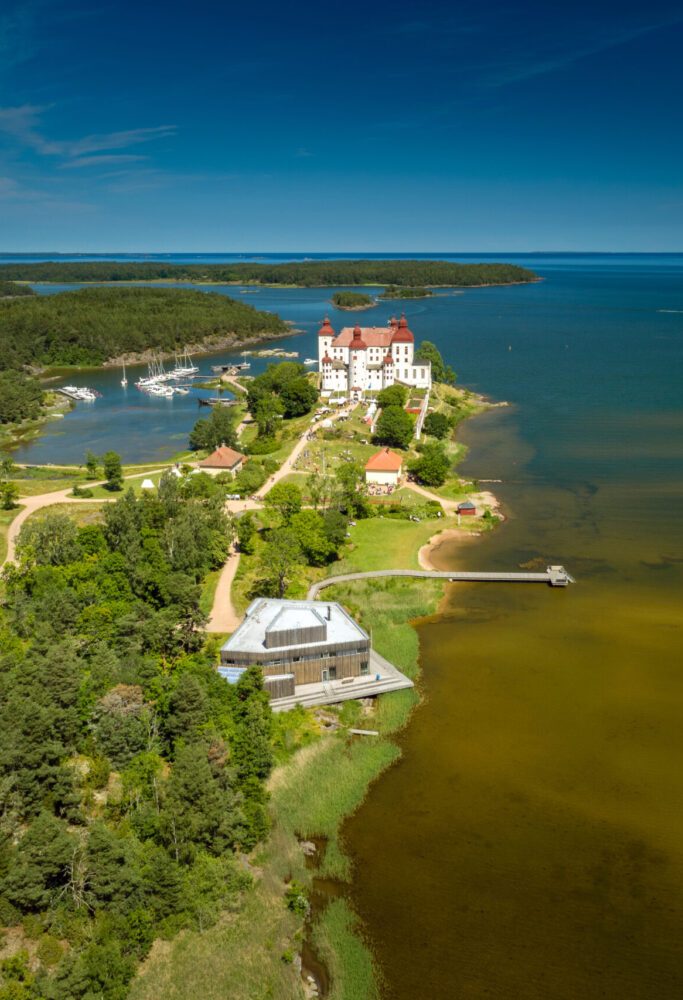 Drönarbild över Läckö Slott en sommardag med skärgården bakom slottet.